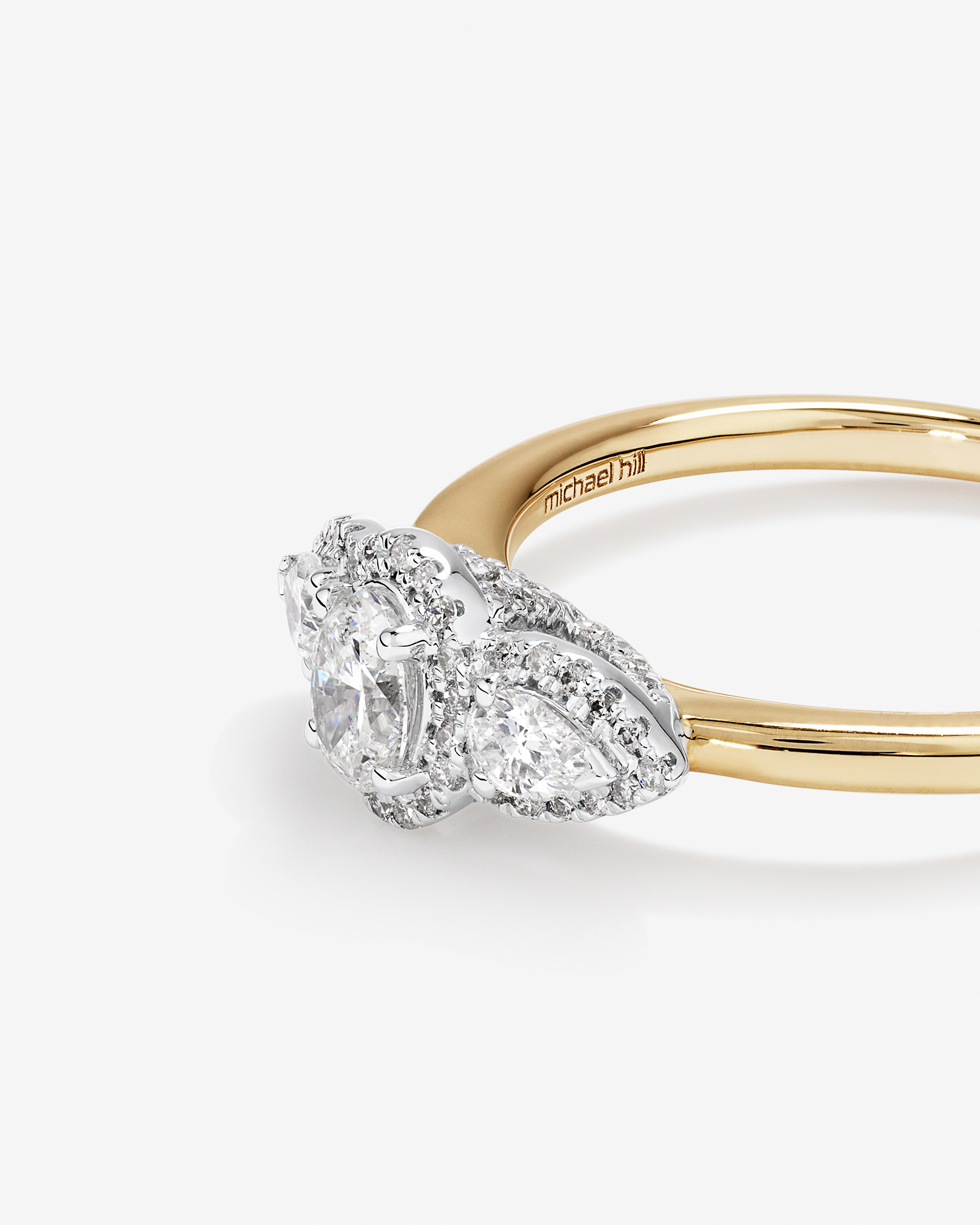 Bague de fiançailles halo en or jaune et blanc 14 carats avec trois diamants ovales et en forme de poire totalisant 0,69 carat.